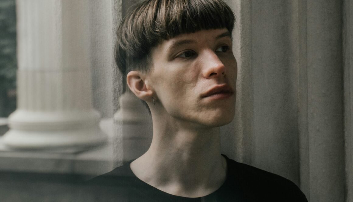 man in black crew neck shirt standing near window