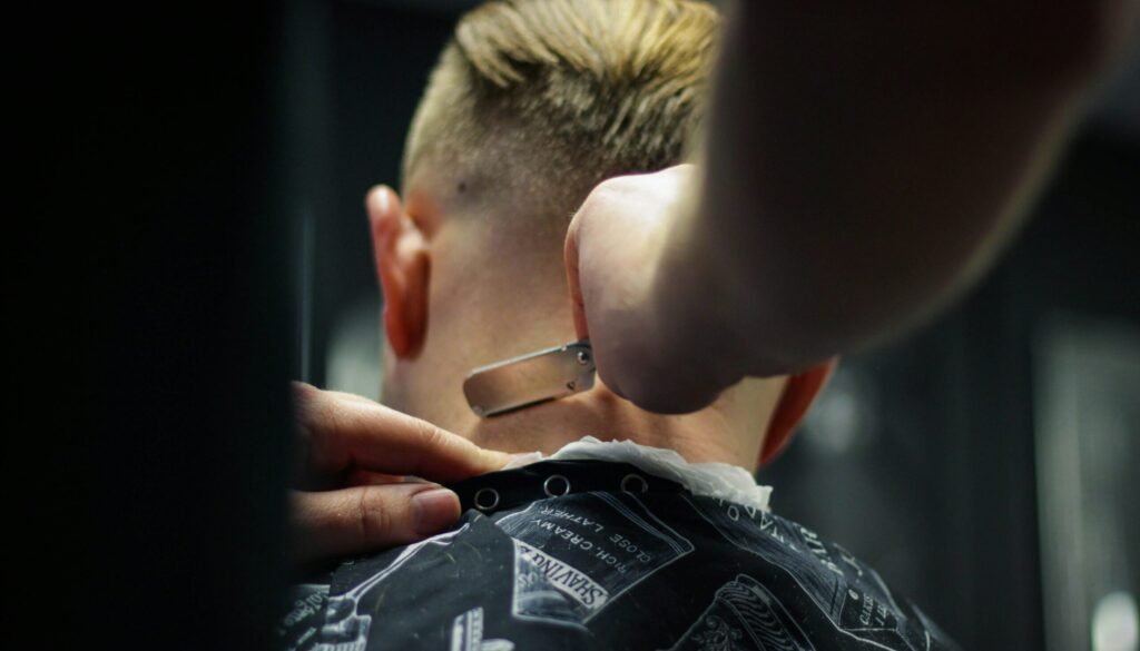 person trimming man's hair